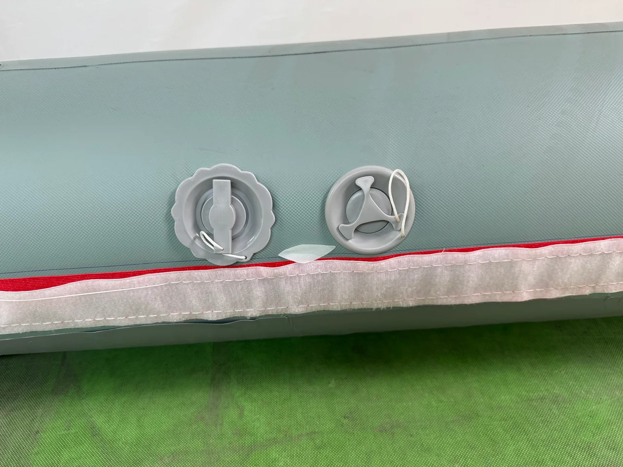 Close view of two valves and a cover attachment edge on an inflatable tent air beam