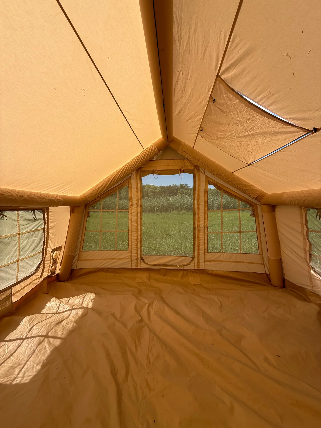 Interior of a large inflatable camping tent showing the usable floor and openings