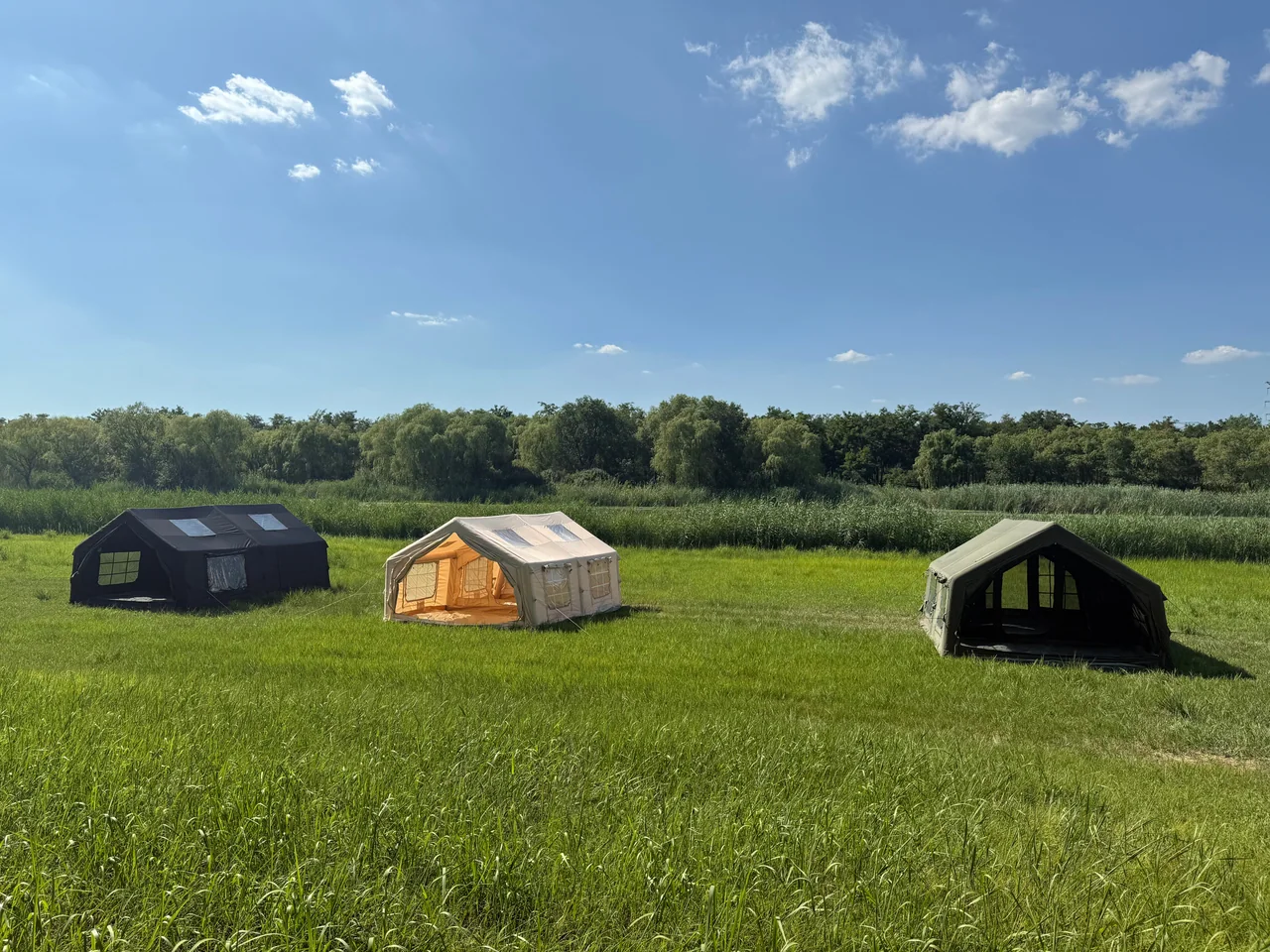 Multiple inflatable camping tent models displayed in an open field